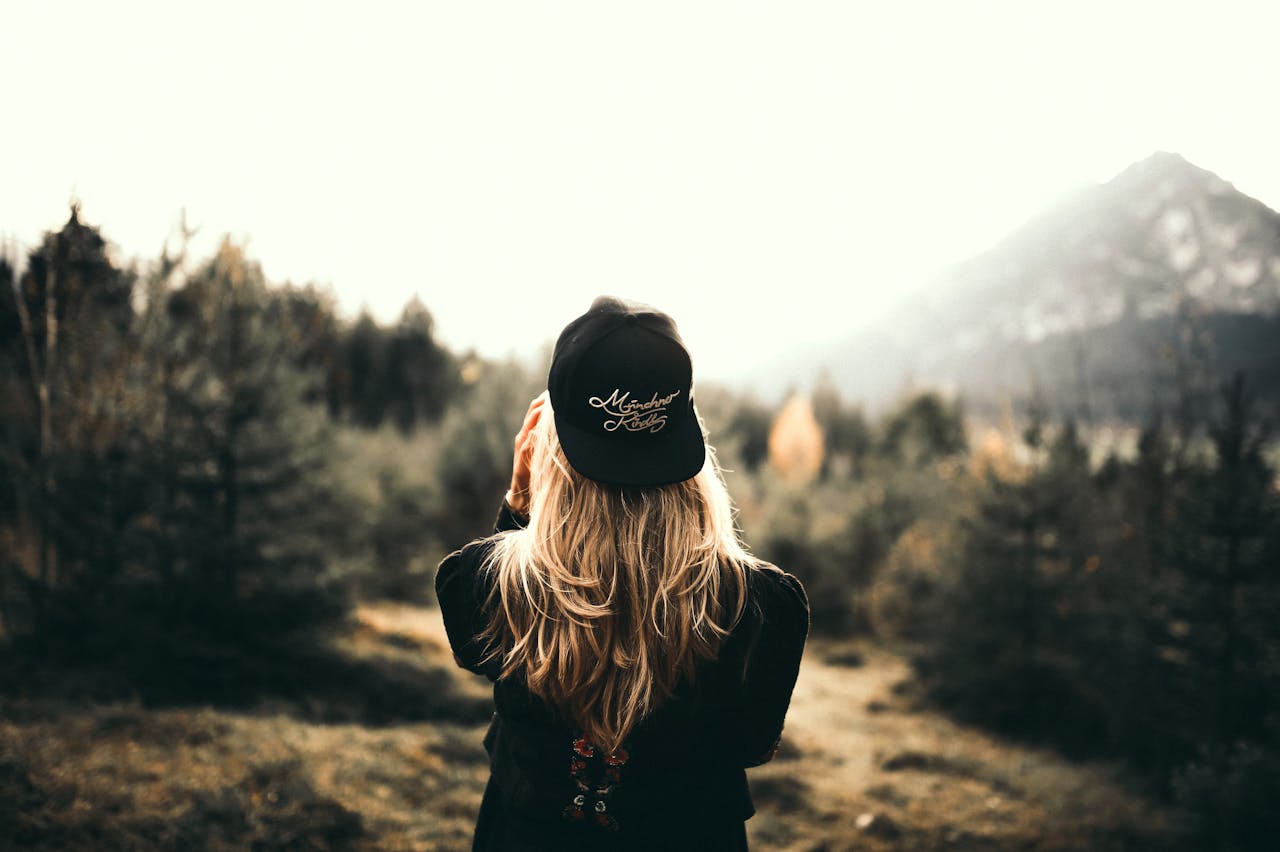 who-we-are A woman in black cap and sweater enjoys a mountain view, embracing outdoor adventure.