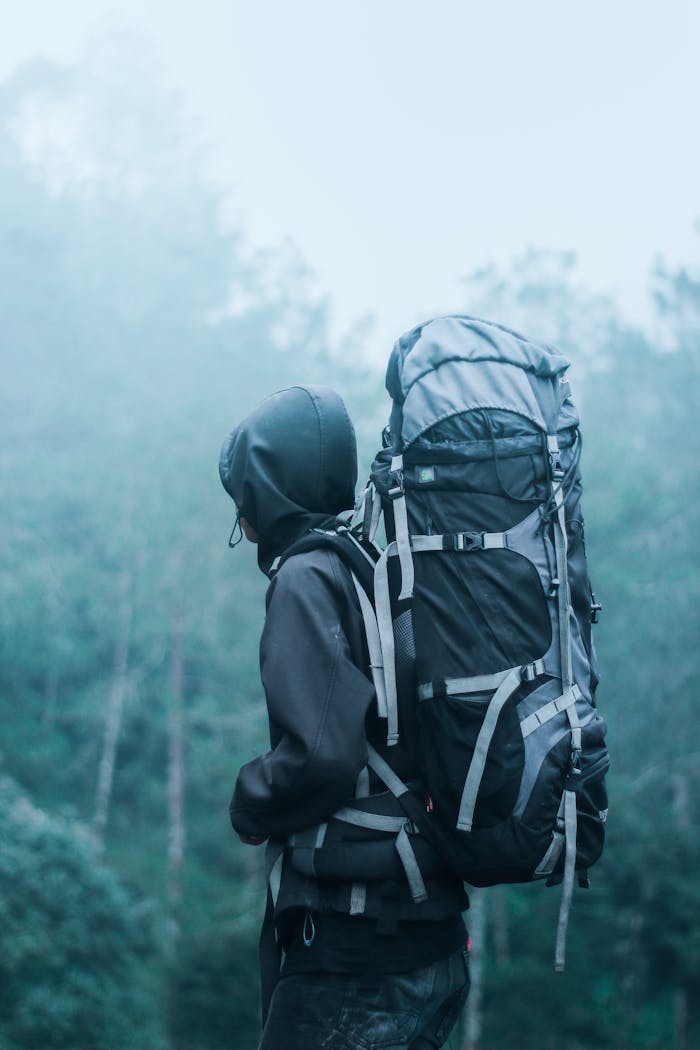 Solo hiker with large backpack in a misty forest, exploring natures serene beauty.